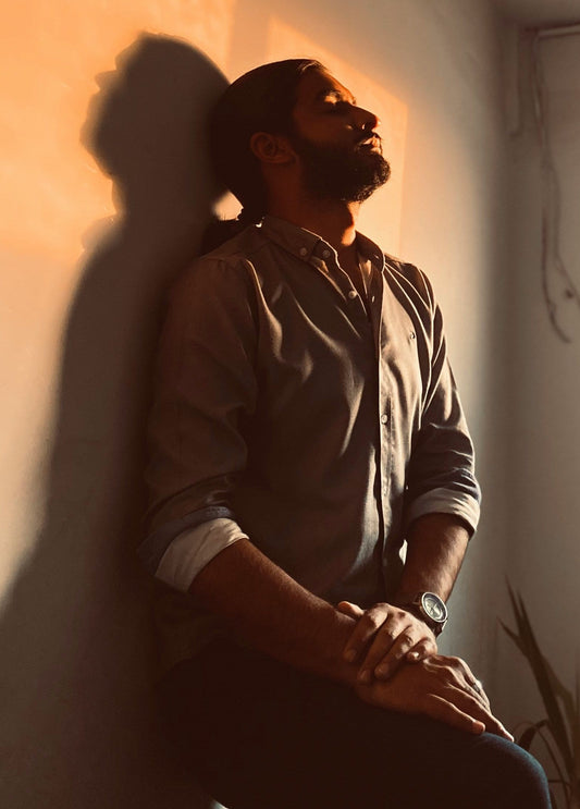 man with a beard standing next to the wall 