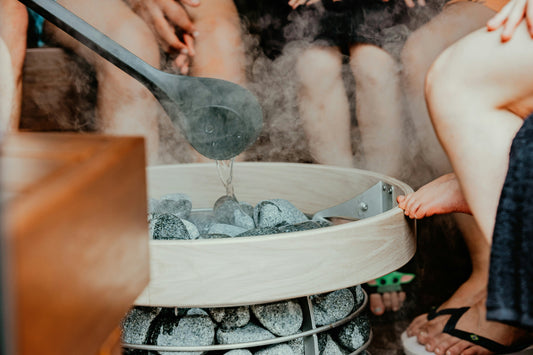 people sitting around the steaming sauna rocks 