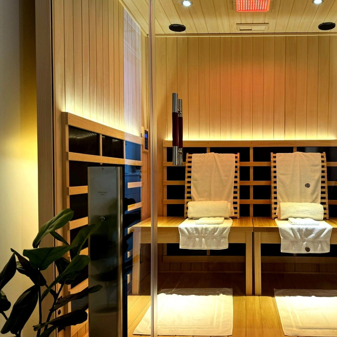 Clearlight Infrared sauna with wooden benches and towels, featuring a plant on the left.