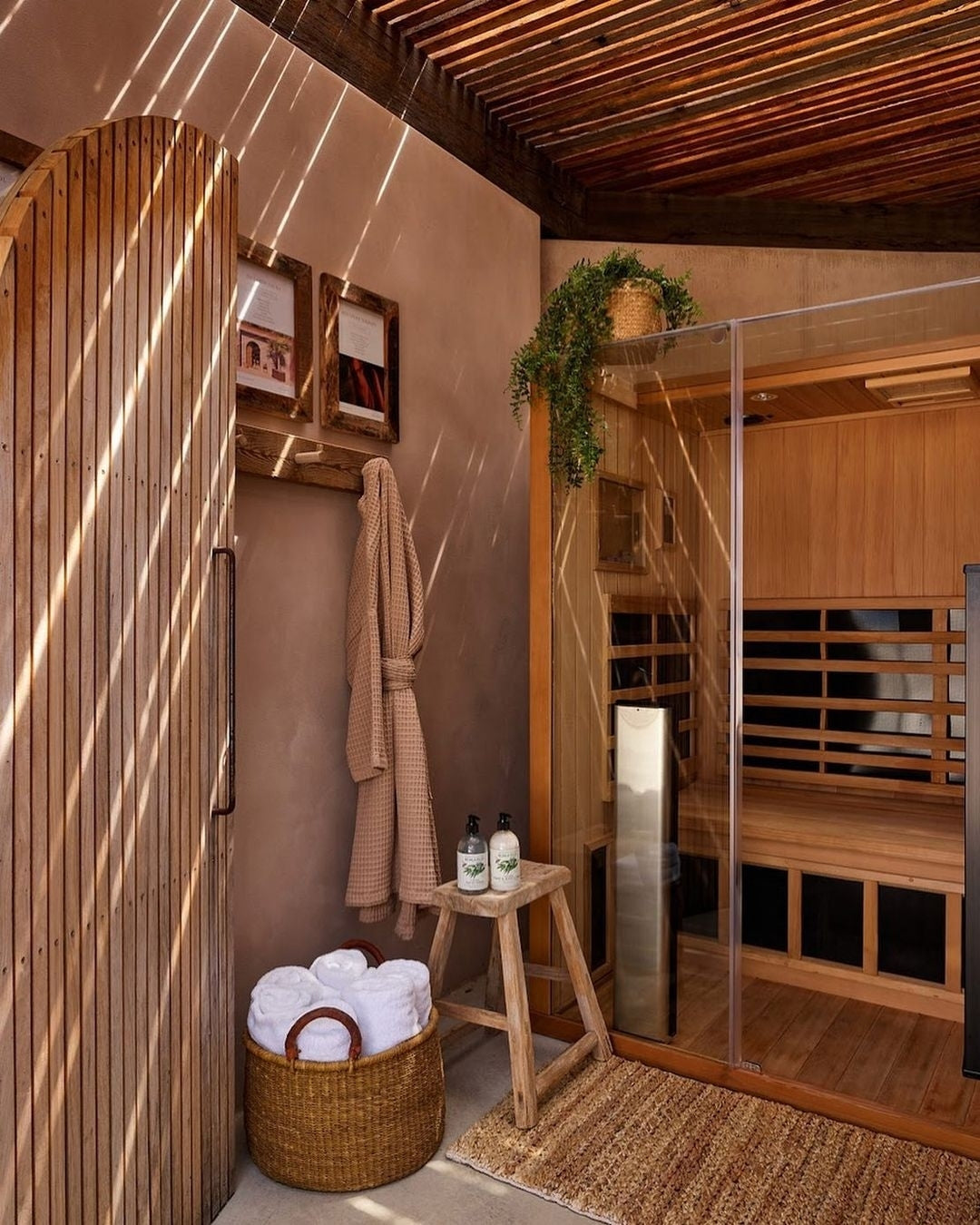 Infrared sauna with wooden interior, towels, and a stool.