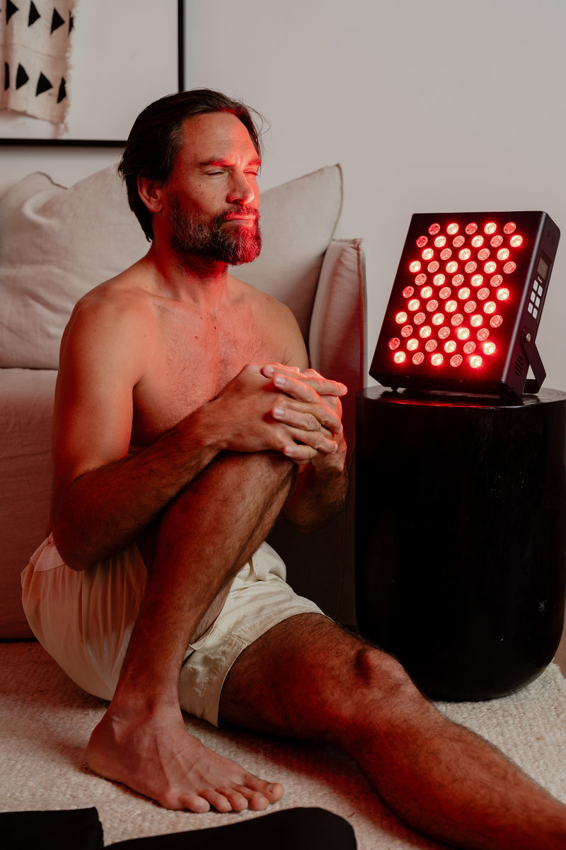 Man applying red LED therapy device to face