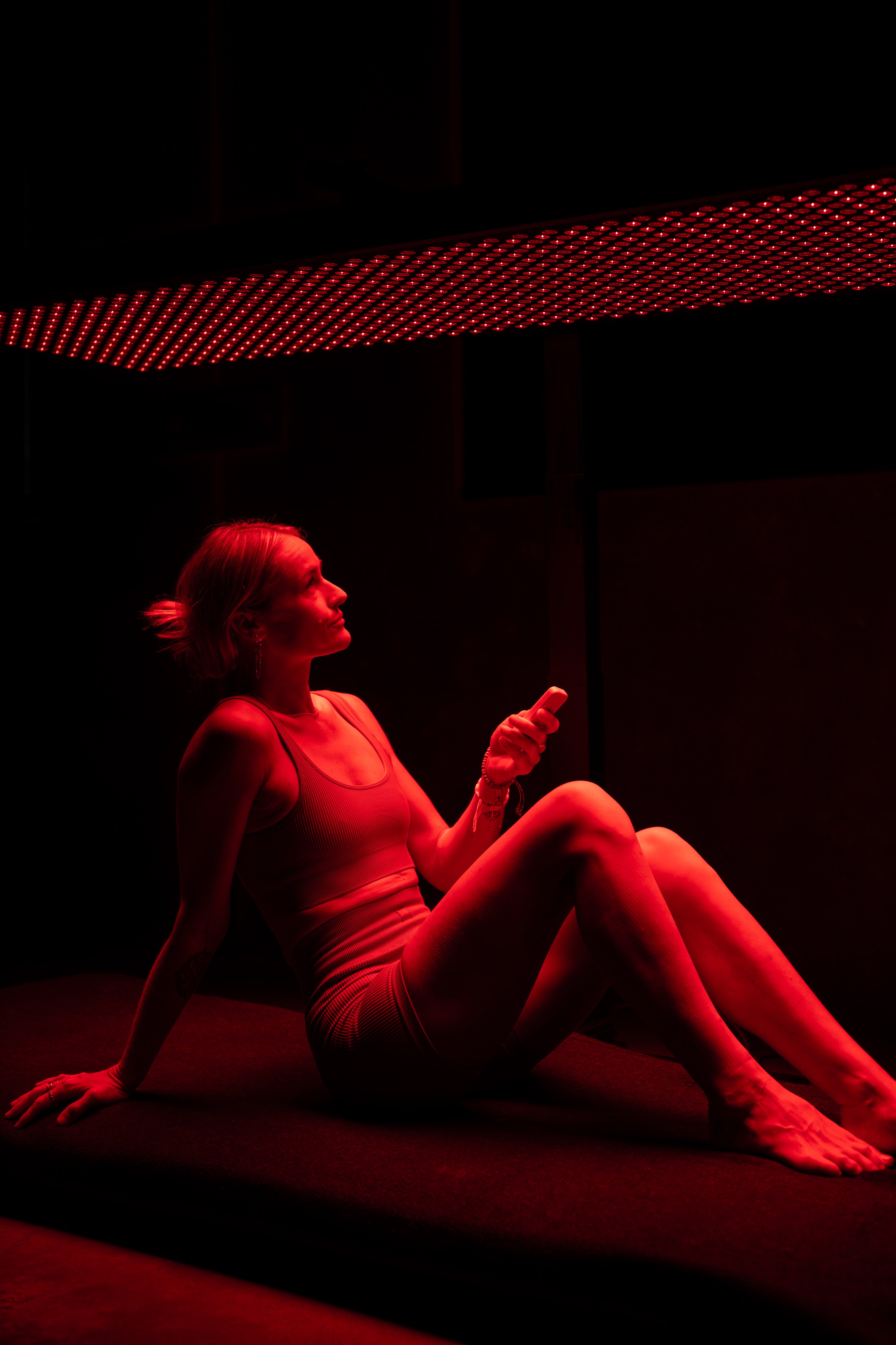 Woman relaxing while using red light therapy panel