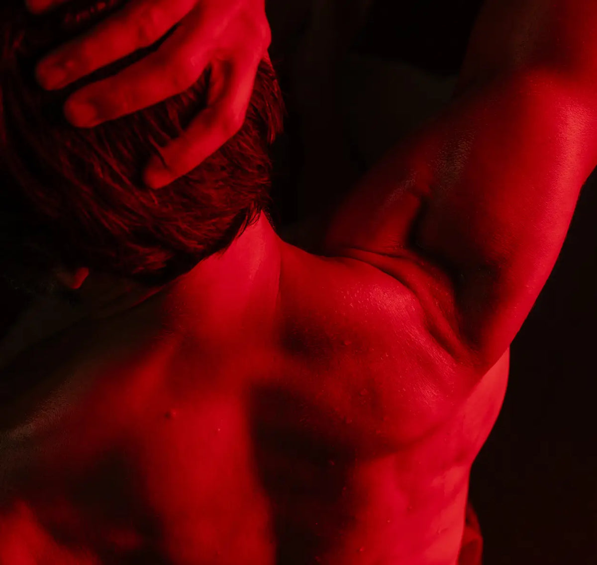 Person applying red light therapy to the shoulder